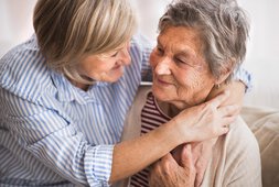 Zwei ältere Damen umarmen sich und lachen sich an | © Halfpoint - stock.adobe.com